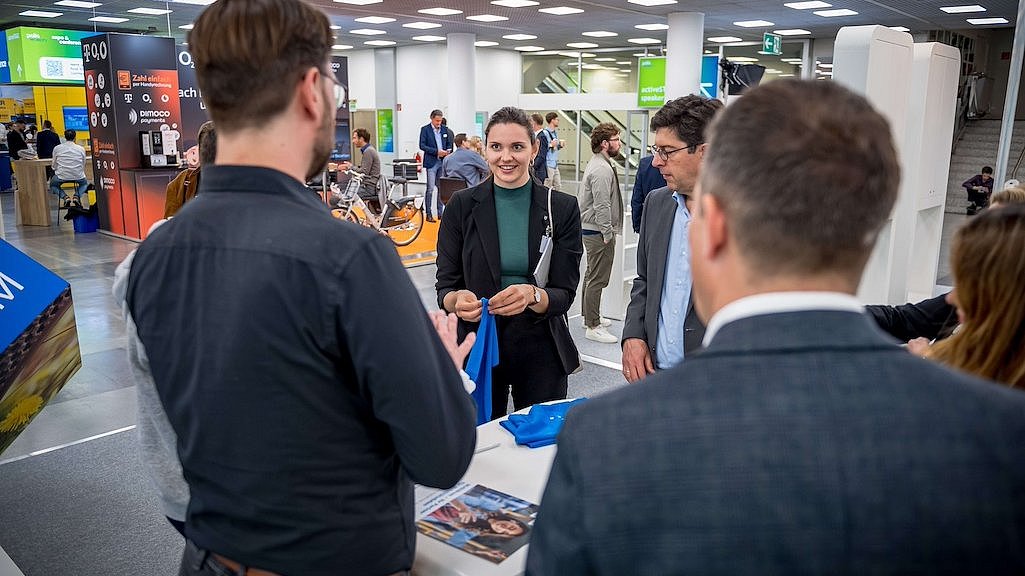 Gruppe von Menschen an einem Messestand auf der polisMOBILITY in Köln mit Werbeartikeln.