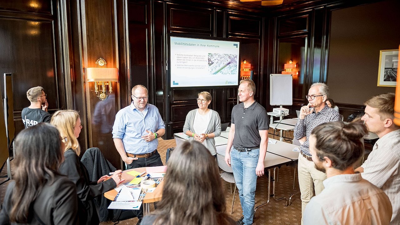 Teilnehmende eines Workshops auf der Kongressmesse polisMOBILITY stehen um einen Tisch mit beschrifteten Kärtchen in einem Besprechungsraum.